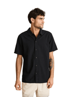 Man wearing a black short-sleeve shirt against a beige background