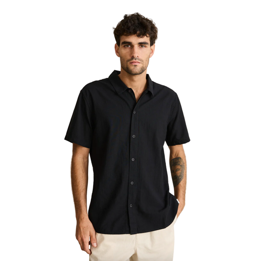 Man wearing a black short-sleeve shirt against a beige background