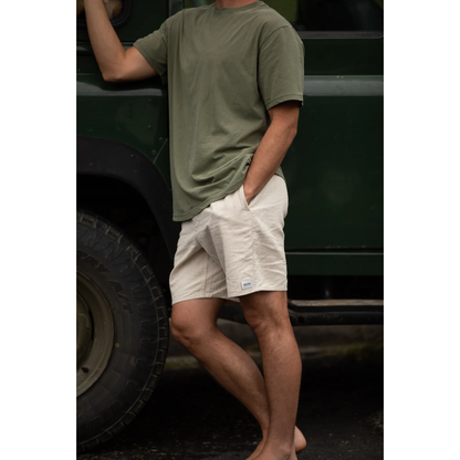 Person wearing a green t-shirt and beige shorts standing next to a vehicle.