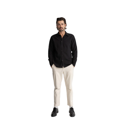 Man wearing a black shirt, white pants, and black shoes on a white background