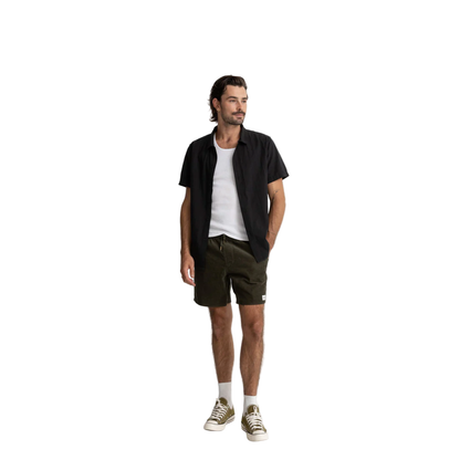 Man wearing a black shirt, white t-shirt, green shorts, and white sneakers on a white background